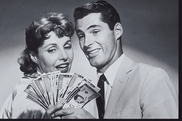 "Smiling couple holding a fan of dollar bills, symbolizing affordable and budget-friendly alternatives that save money"
