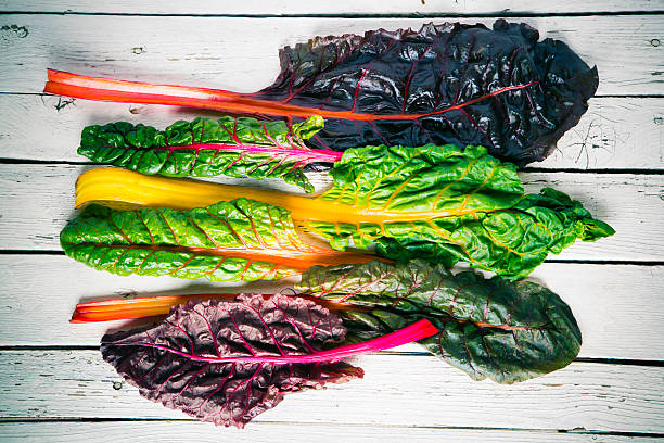 Freshly harvested rainbow chard leaves on a wooden surface, showcasing solutions to common leafy green growing problems in containers.
