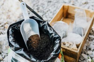 Organic slow-release fertilizer (vermicompost) scoop in a bag beside a wooden crate — winter fertilizer for balcony and container plants; safe feeding tips for Indian winters.