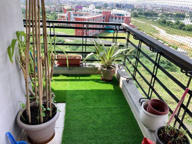 Small apartment balcony with potted plants, railing planters, and artificial grass—showing how the right pots and placement help plants thrive in limited space.