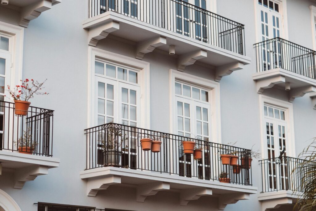 Minimal balcony garden with railing planters and hanging pots showing smart use of vertical space for small-space gardening on a budget.