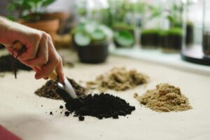 Hands mixing different potting soil ingredients for a long-lasting container gardening soil system with organic matter, aeration materials, and moisture-retaining soil mix for healthy potted plants
